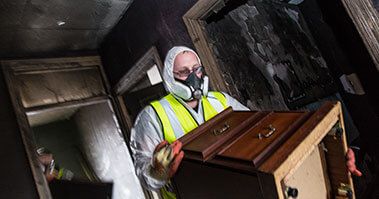 A worker removing burnt furniture
