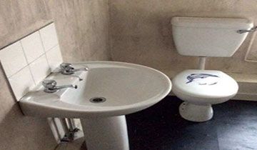 Inside of a bathroom with a white sink and toilet