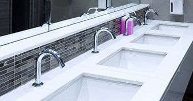 A row of sinks with some pink soap